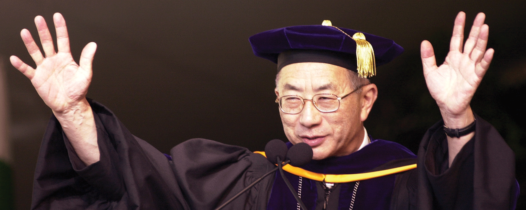 Bob Suzuki waves during a commencement ceremony.