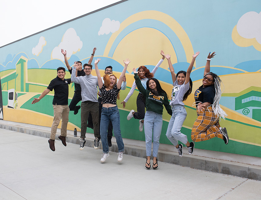 Students jumping joyfully in front of Parking Structure II mural