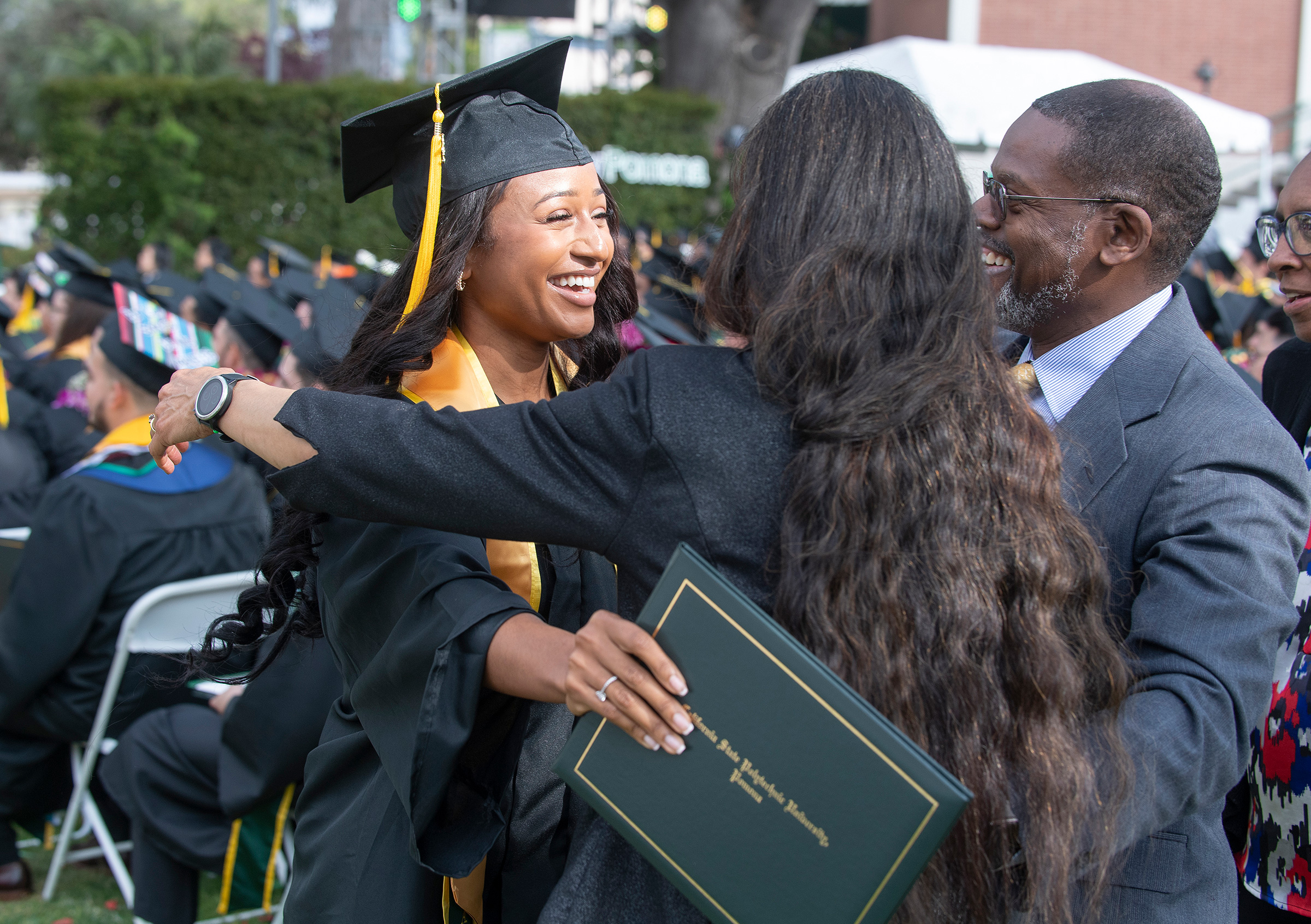 A graduate smiles and hugs her family