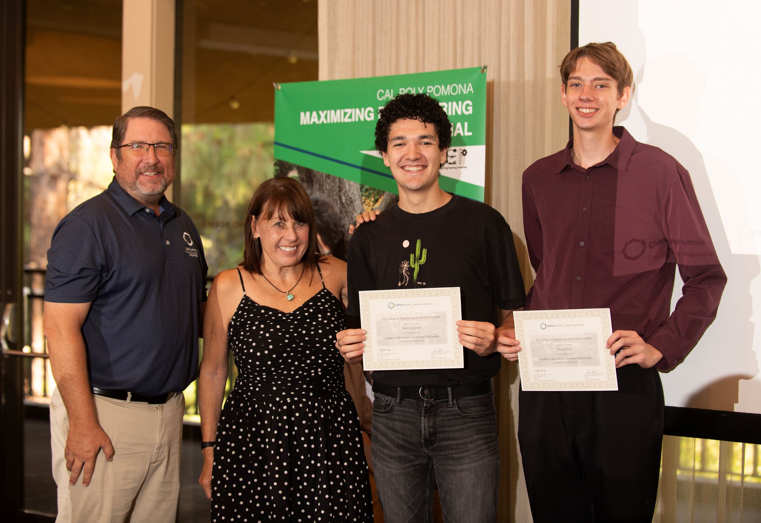 Two student hold up scholarship certificates with their parents.