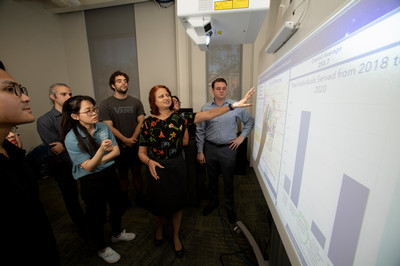 Female presenting in front of student on a screen