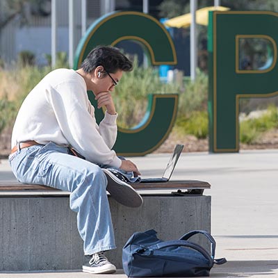 grad student sitting outside by a cpp sign