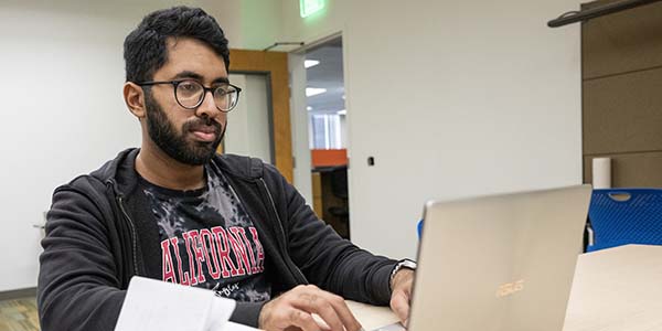 student in dorm looking at laptop