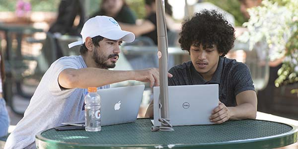 students outside at a table on a laptop