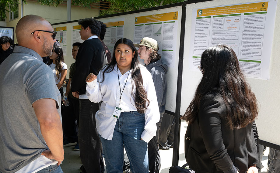 A female student makes a poster presentation at the FYE Poly X Showcase.