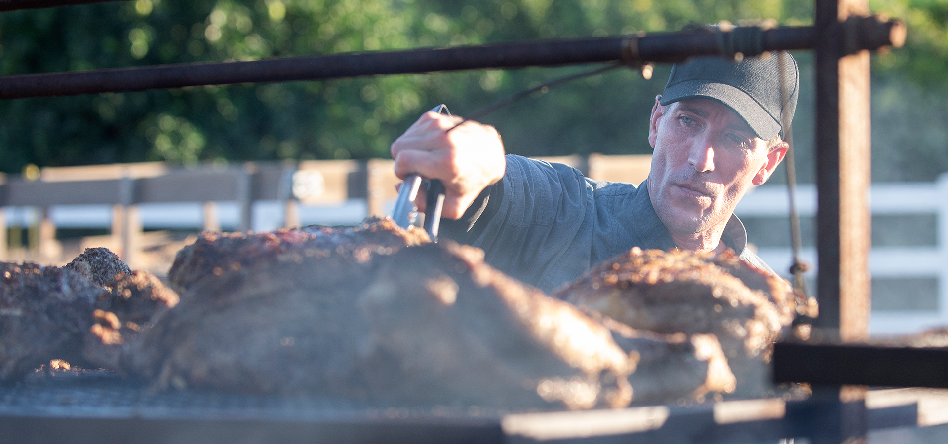 A cook cooks a huge slab of meat on a grill