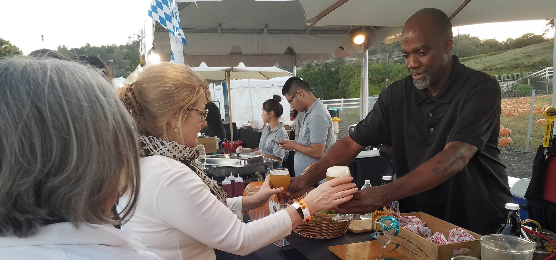 A male server hands a woman two glasses of beer