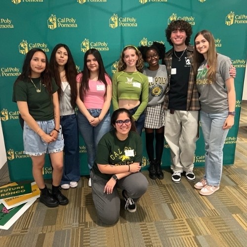 students gathered in front of green backdrop