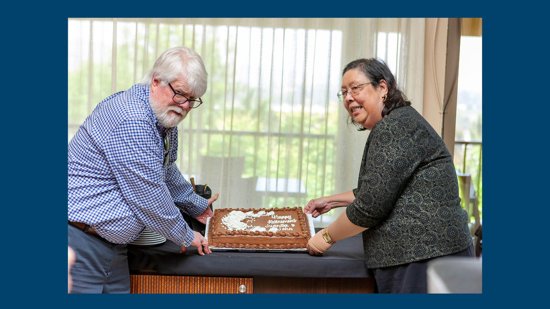 John Wallace and Juanita Roxas hold up retirement cake