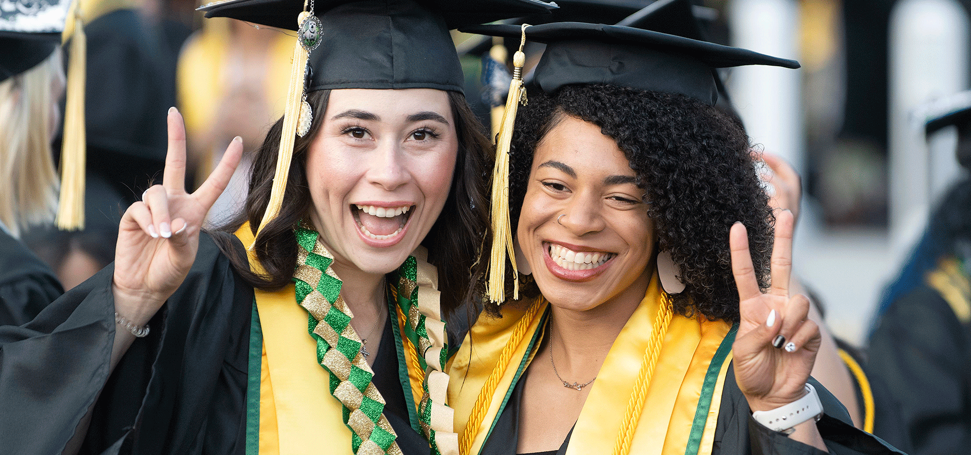 Two female AG graduates smile and give the peace sign.