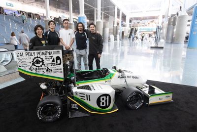 Cal Poly Pomona engineering students standing behind their Formula race car at the 2023 LA Auto Show.