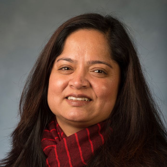 dr.preeti wadhwa wearing a black coat and red top.