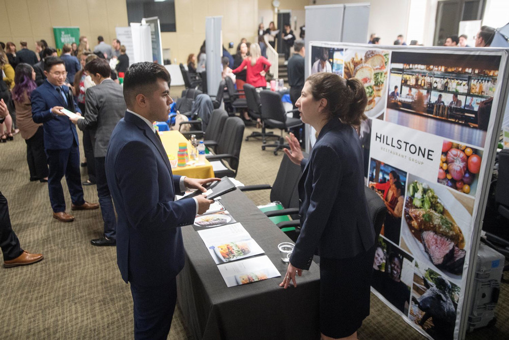 Two people talking at the Hillstone's Hospitality Career Expo booth