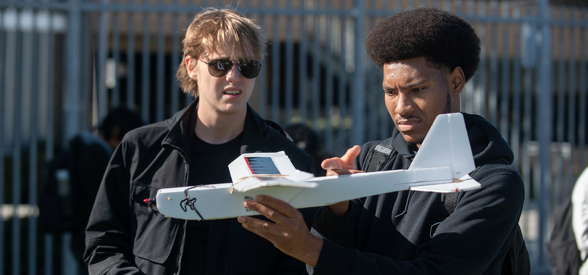 Two male students work together with a plane.