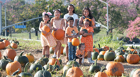 A group of children hold pumpkins at the Cal Poly Pomona pumpkin patch.