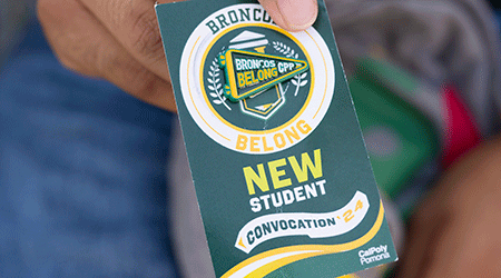 A student holds a Broncos Belong pin from the New Student Convocation. 