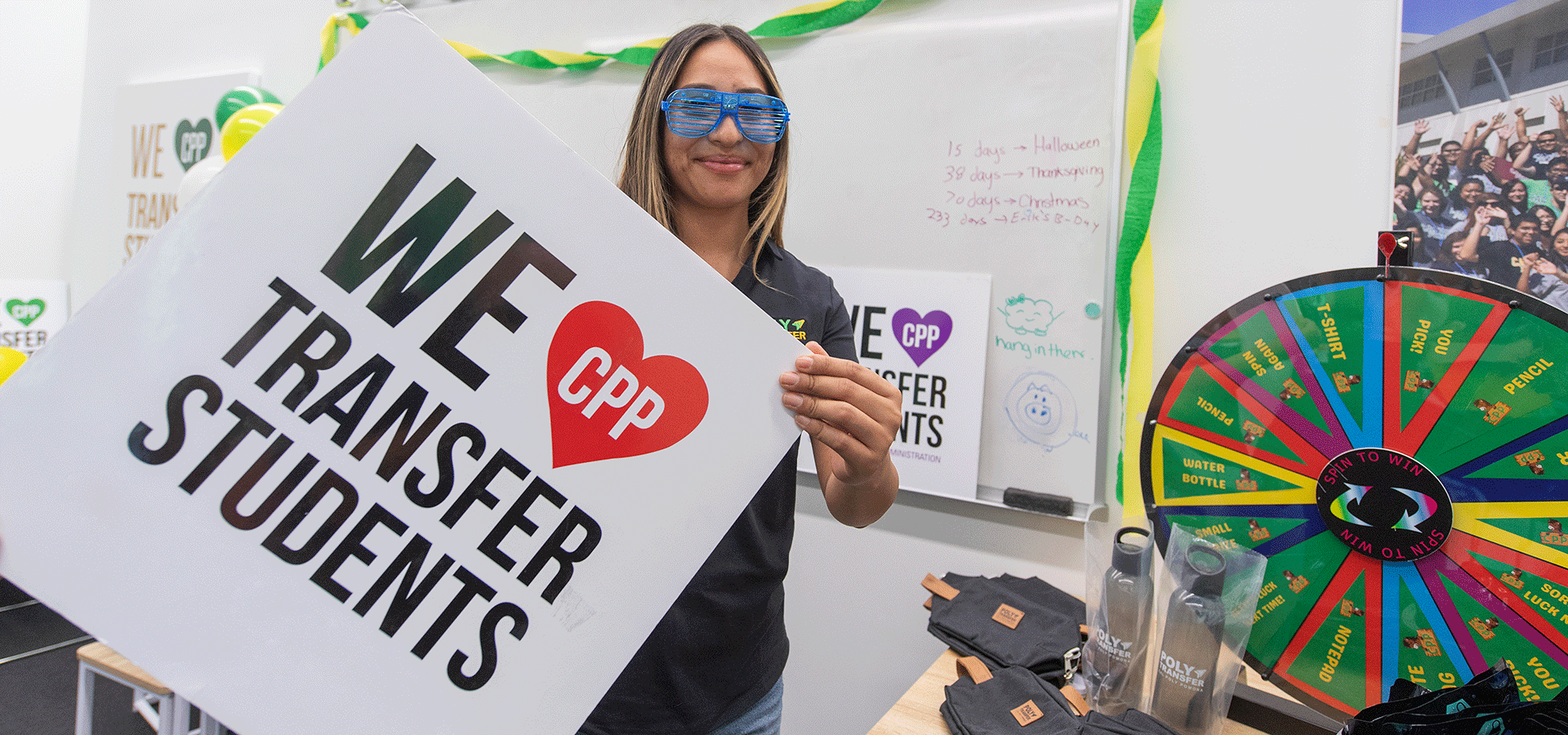 A female student holds a sign that says "We Love Transfer Students"