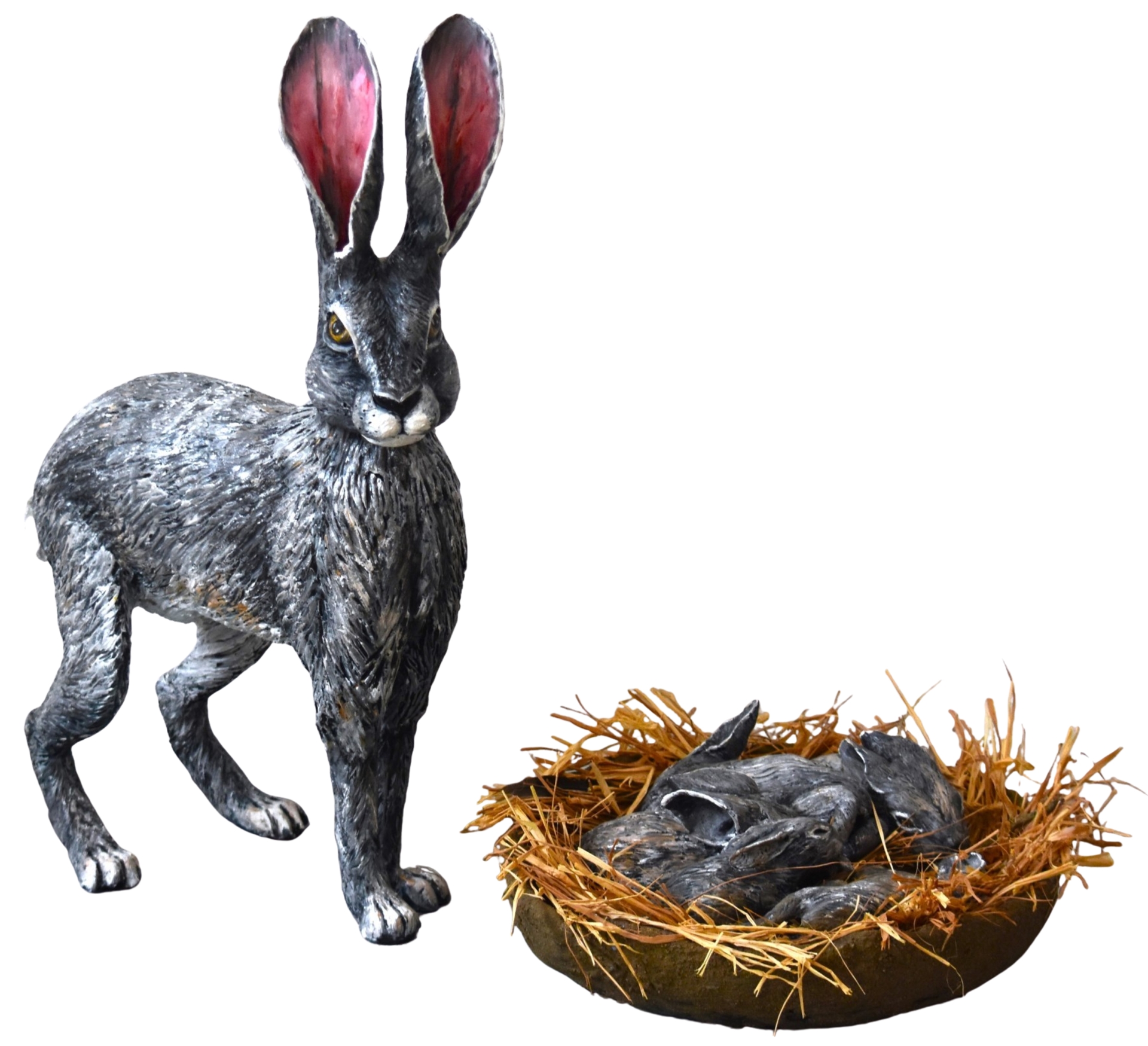 A sculpture of a gray hare with large pink-tipped ears standing beside a nest filled with sleeping baby hares on a bed of straw.