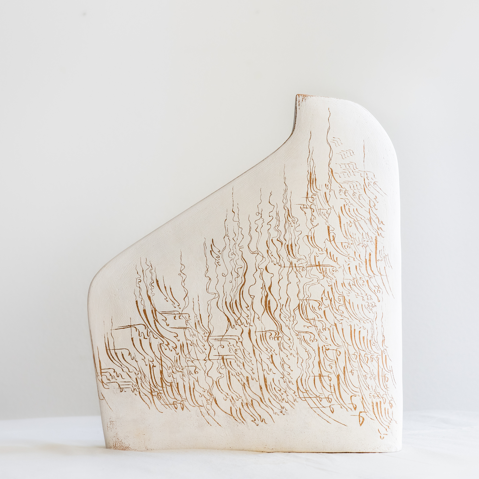 A minimalist ceramic sculpture with a smooth, off-white surface, featuring delicate, hand-carved line patterns resembling flowing plants or waves, creating a natural and organic design.