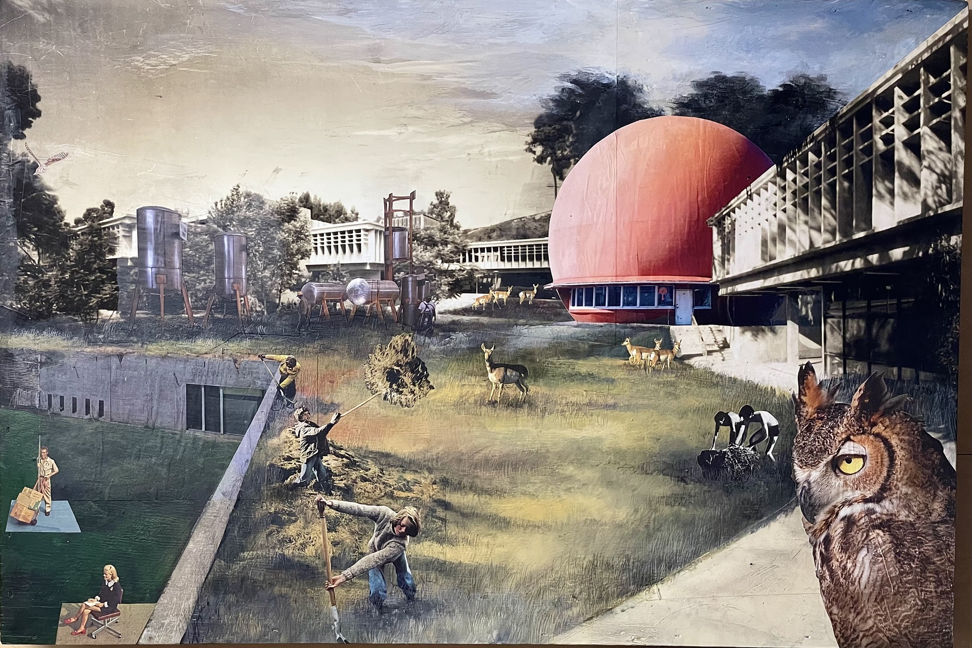 A surreal collage featuring people engaged in various activities in a grassy field, surrounded by industrial tanks, deer, and a large red spherical building, with an owl gazing intently in the foreground.