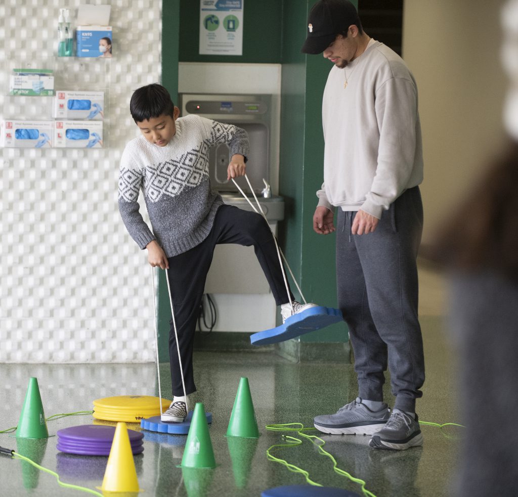 A child works with a student therapist in an obstacle course.