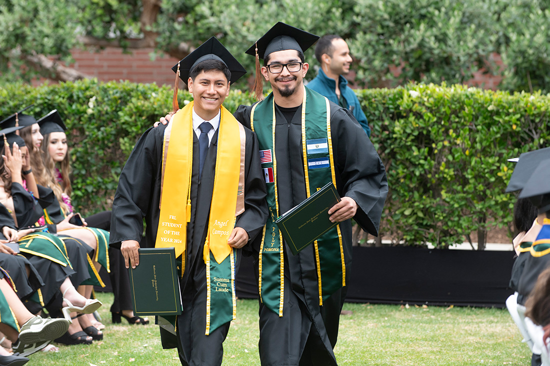 Two male graduates stand together and smile