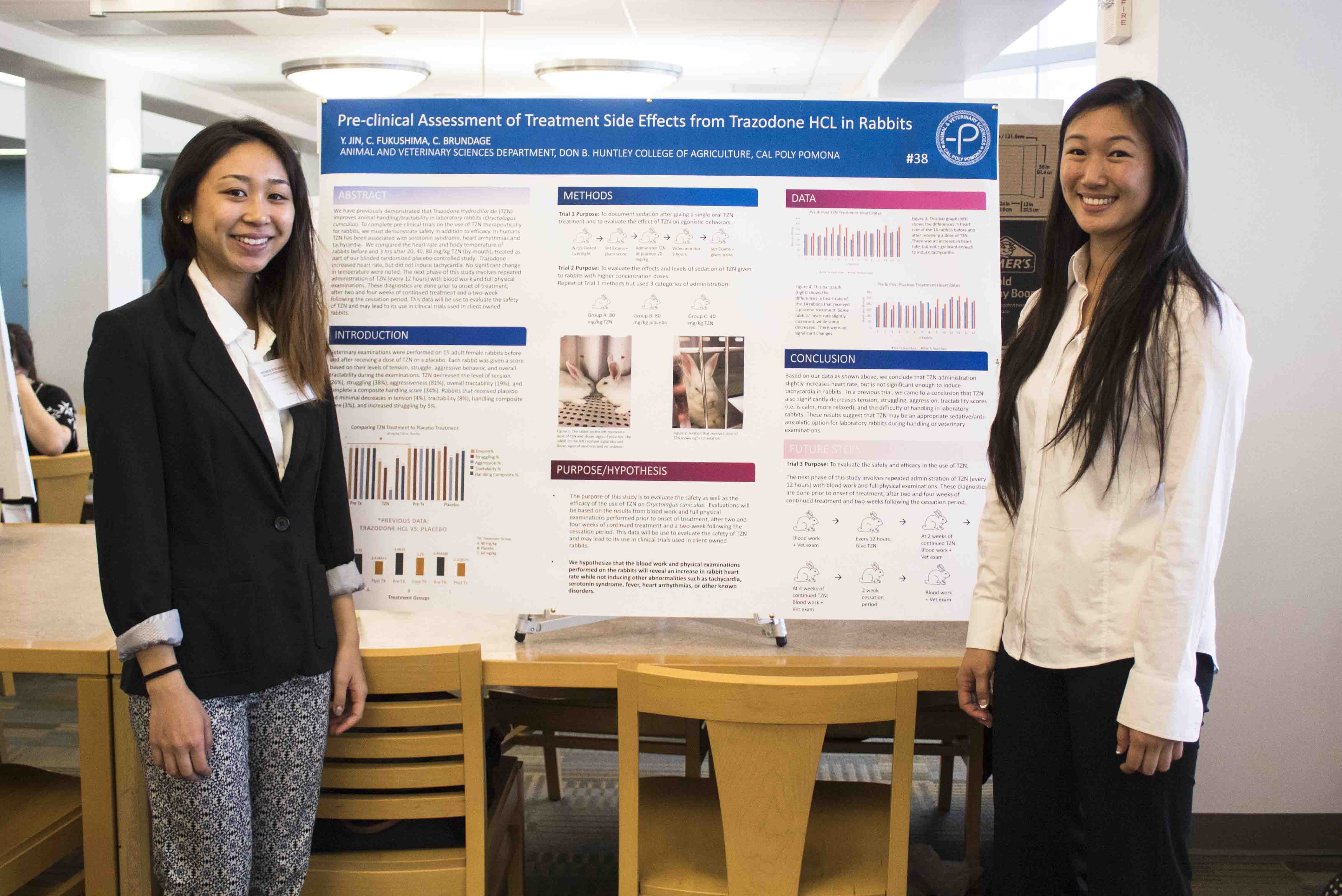 two Students posing in front of their poster at research event