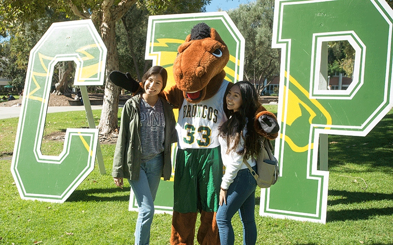 Two female students pose with Billy during New Student Convocation