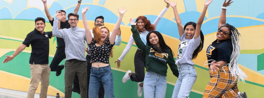 Students jumping in front of a mural