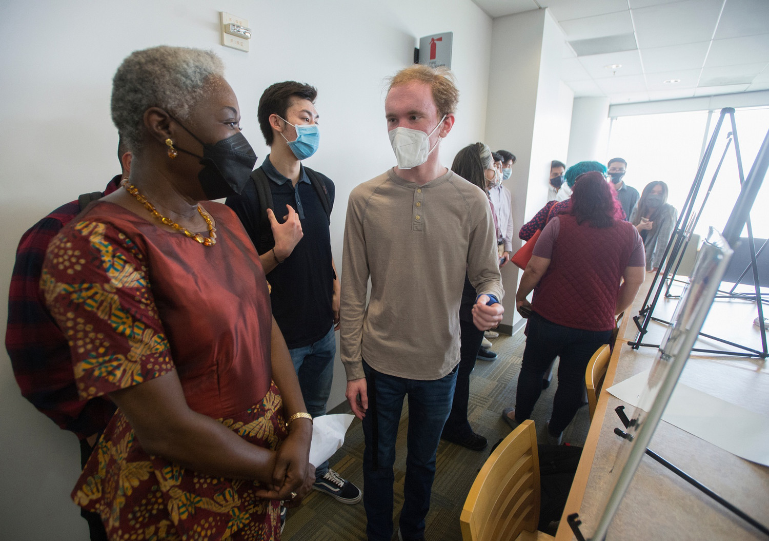 Photo of Dr. Sawyerr chatting with a student about their PolyX project poster during the PolyX Showcase event.