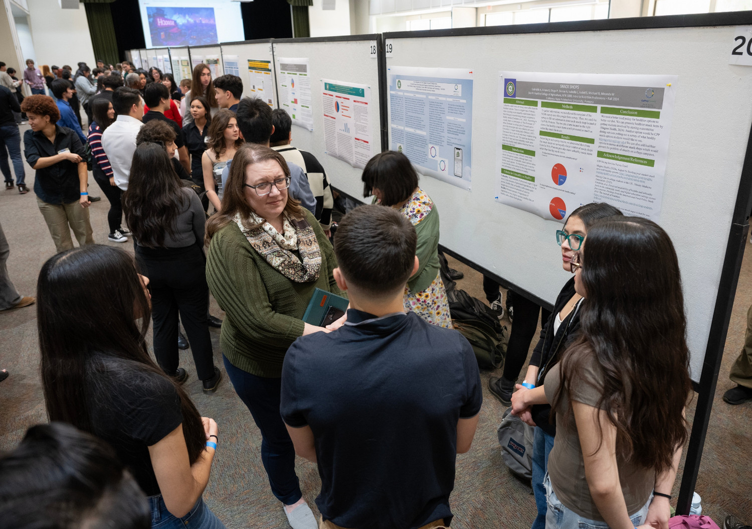 Group of students conversing with faculty during the PolyX Showcase, where students can present their research projects and connect with professionals at CPP.