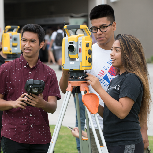 Three students work together with a surveying machine