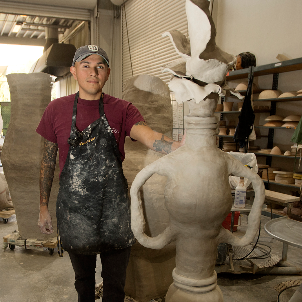 A student stands with his sculpture