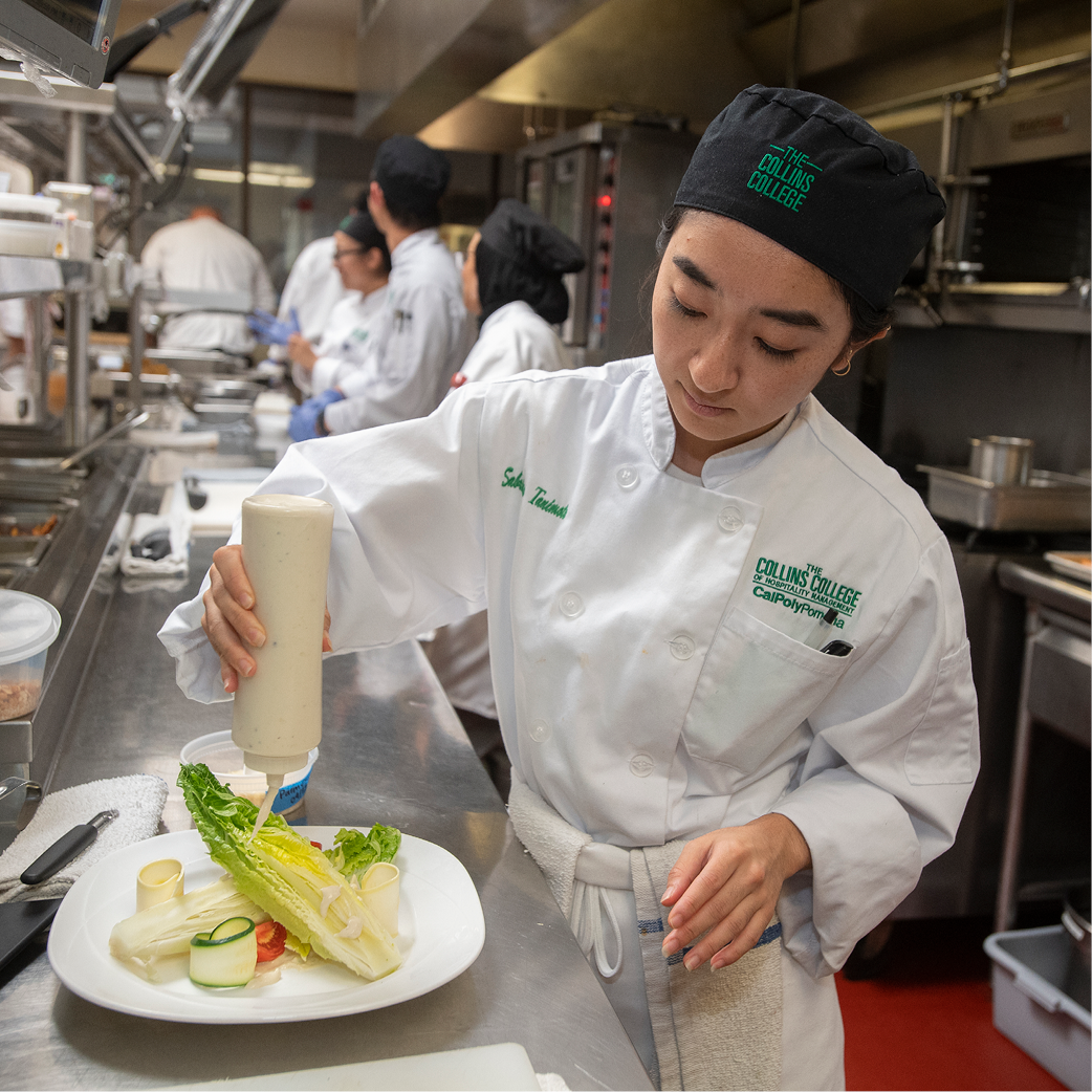 A student puts dressing on a salad